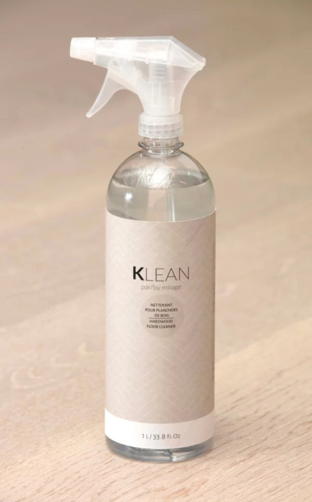 A Klean parby managed non-toxic pine cleaner spray bottle with a clear plastic trigger sprayer and a beige label, set on a light wood surface.